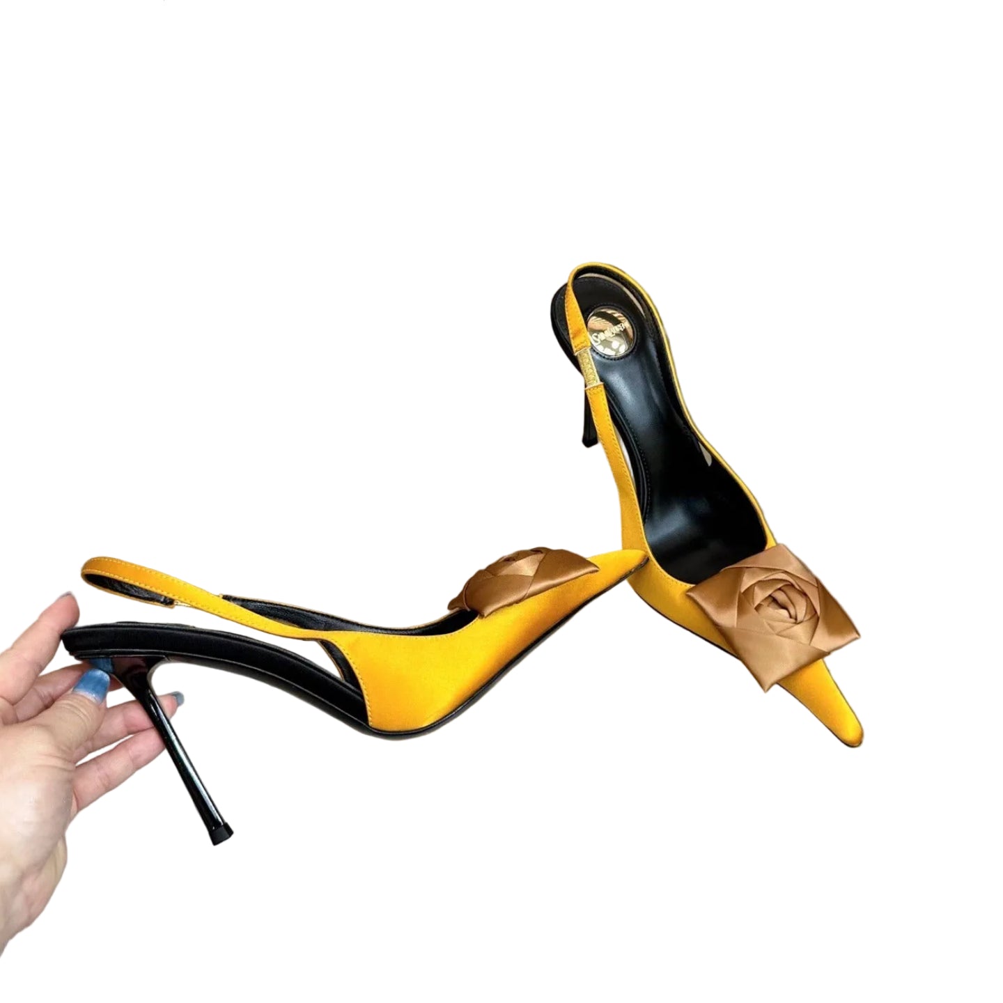 Yellow high-heeled shoes with black accents on a reflective surface.