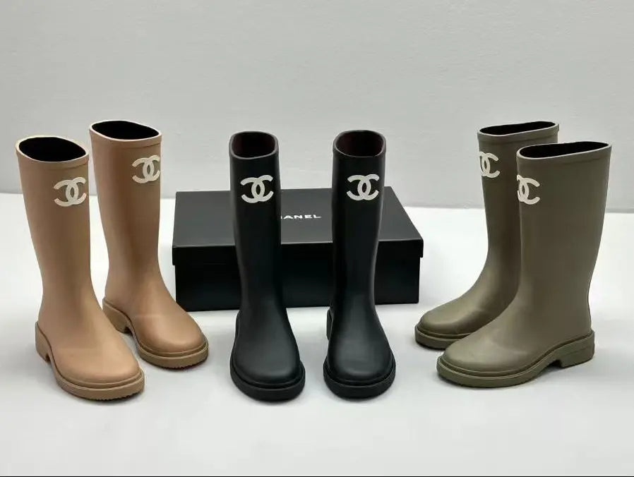 Set of four rain boots in beige, black, and gray with Chanel logo on a white background
