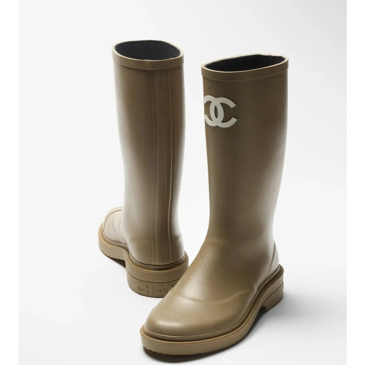 Pair of beige rain boots with a logo on a white background
