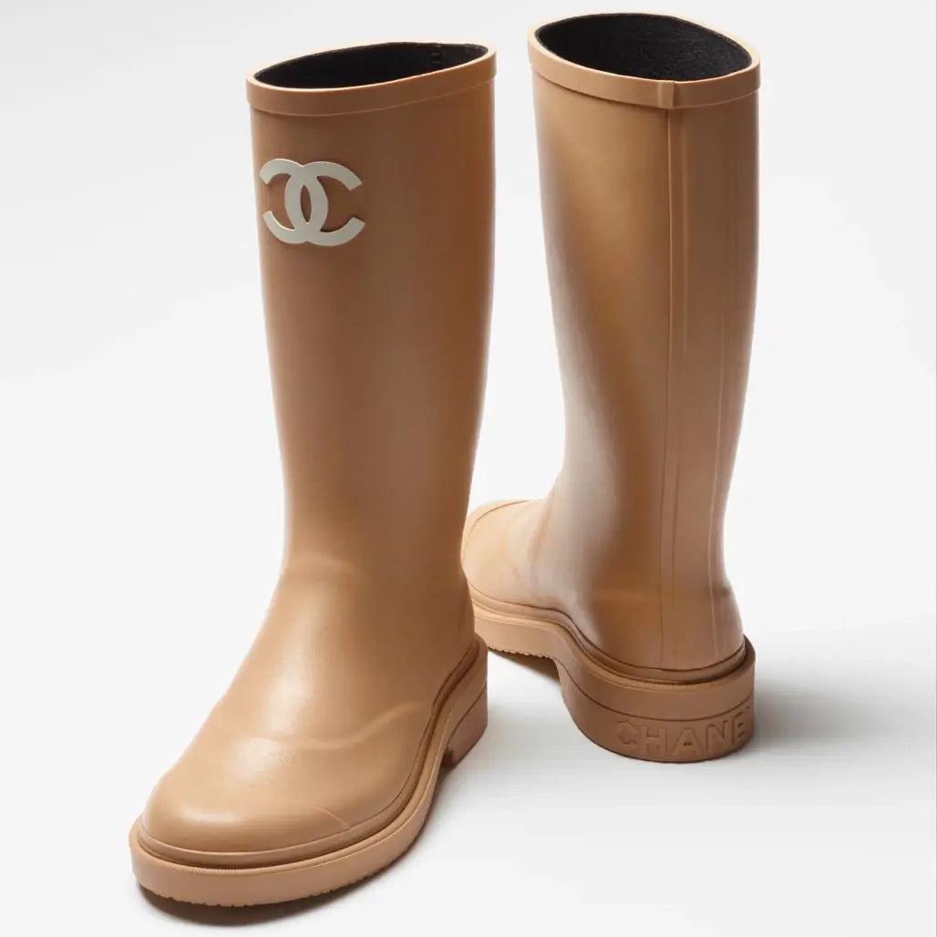 Tan rain boots with Chanel logo on a white background