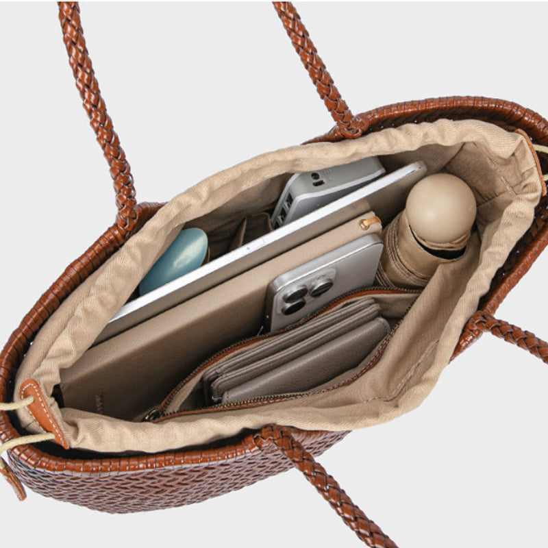 Open brown leather handbag with items inside on a light gray background