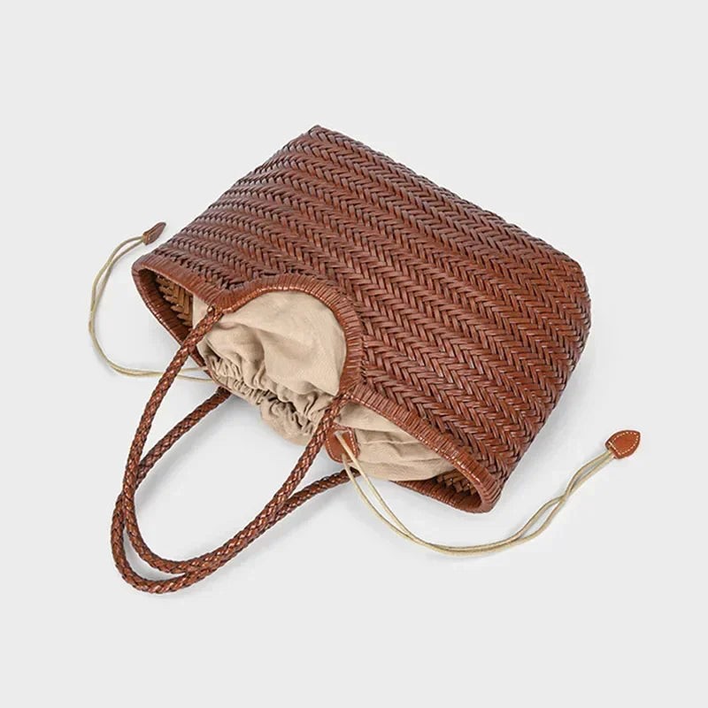 Brown woven bucket bag with beige interior on a light gray background