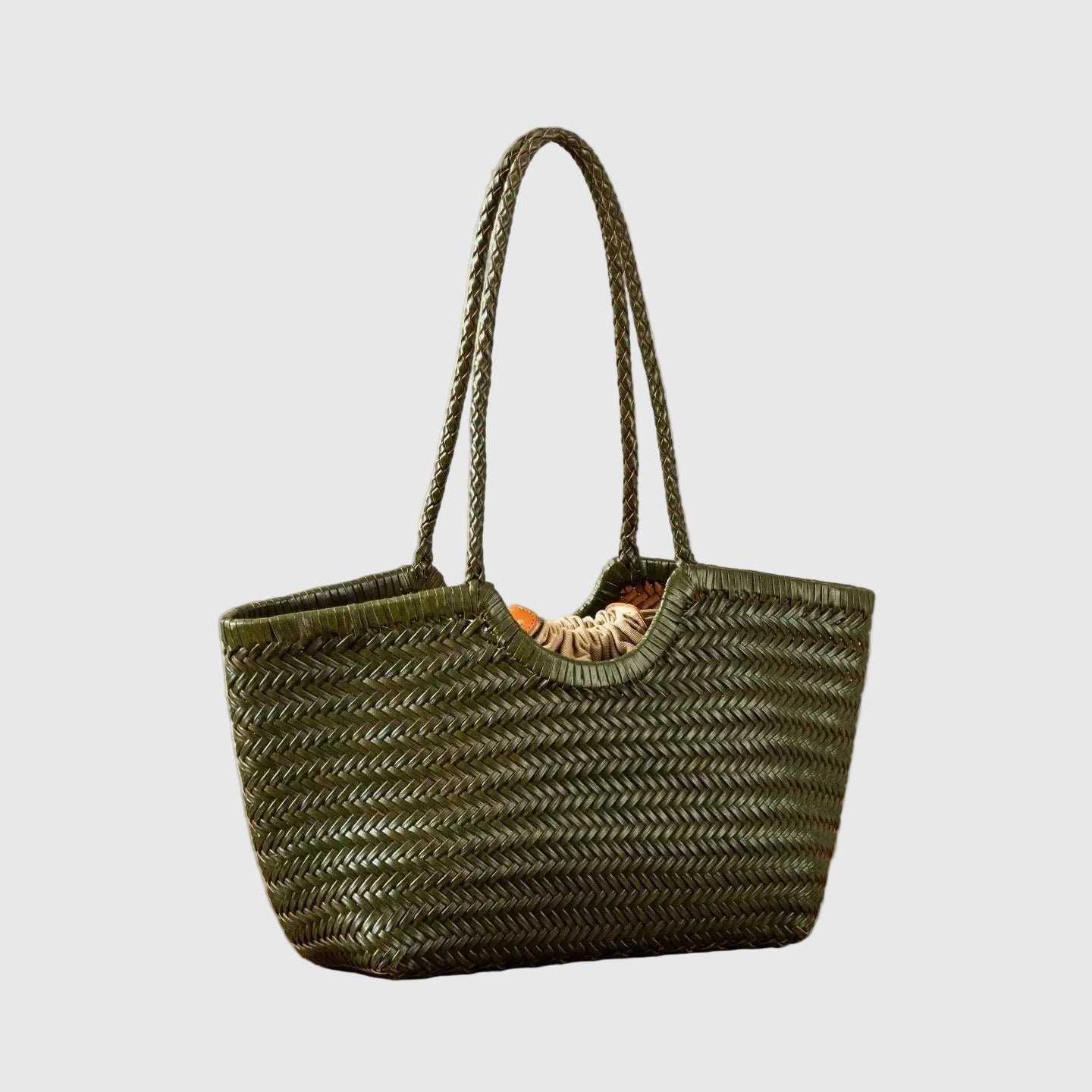Woven handbag on a wooden table with a plant in the background