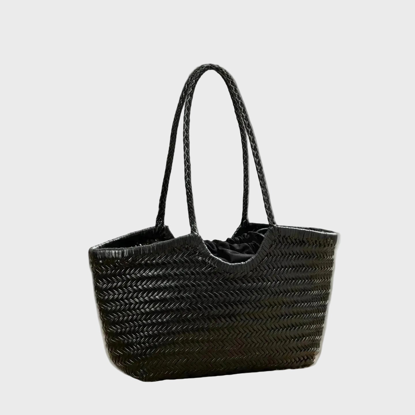 Black woven handbag on a wooden surface with a blurred background