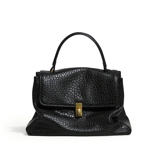 Black leather handbag with a gold clasp on a white background