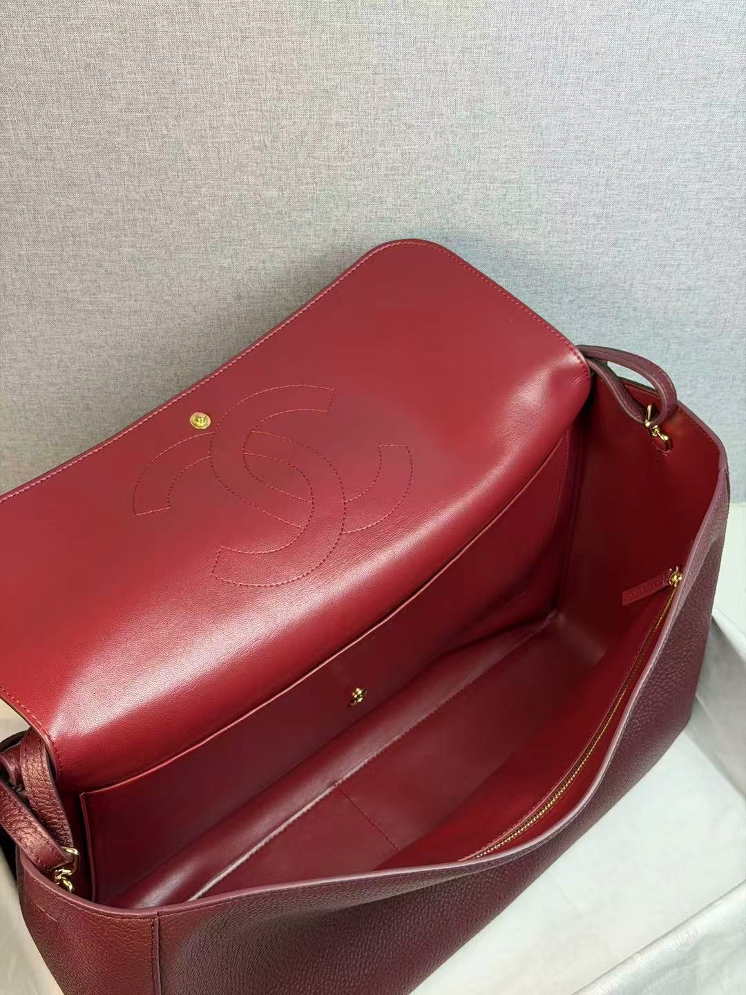 Burgundy handbag with a visible brand logo on a light gray background