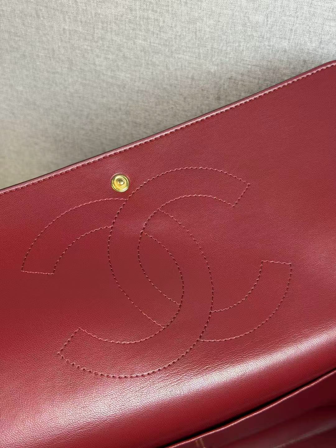 Burgundy leather wallet with Chanel logo on a beige background