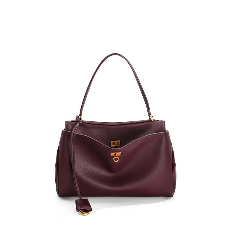 Burgundy handbag with gold accents on a white background