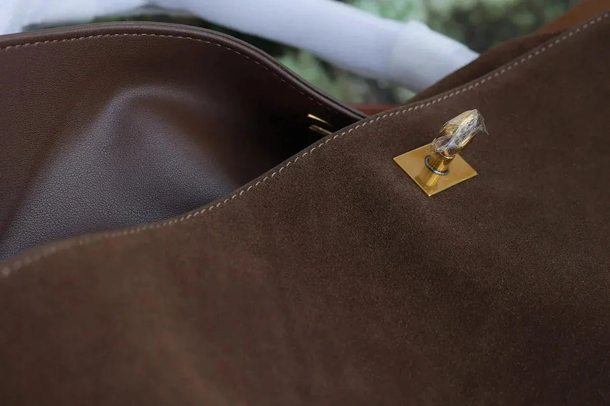 Brown leather handbag with a gold clasp on a blurred background
