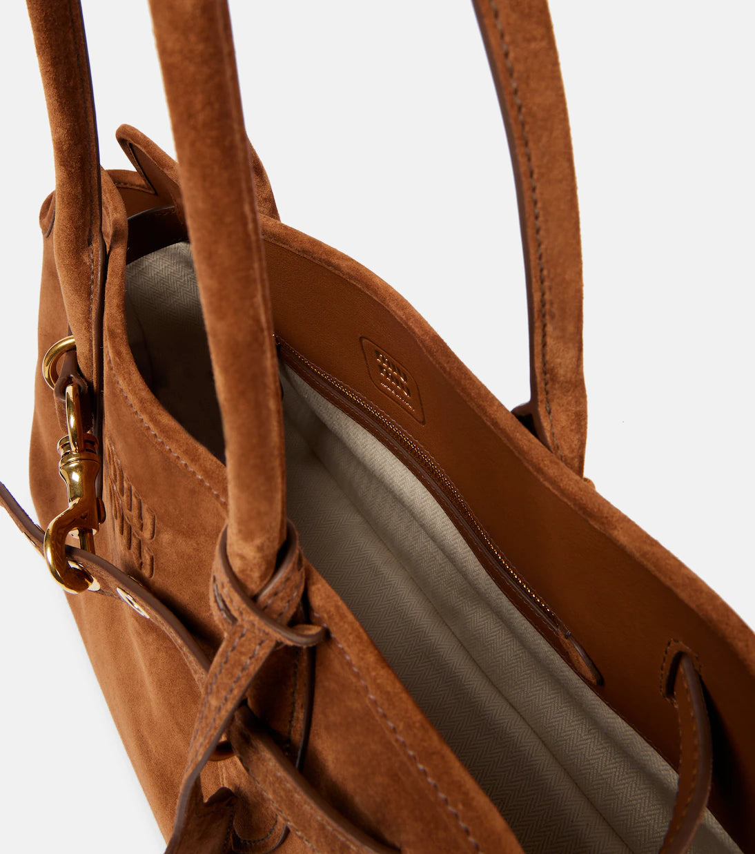 Close-up of a brown leather handbag with visible brand logo on a light gray background