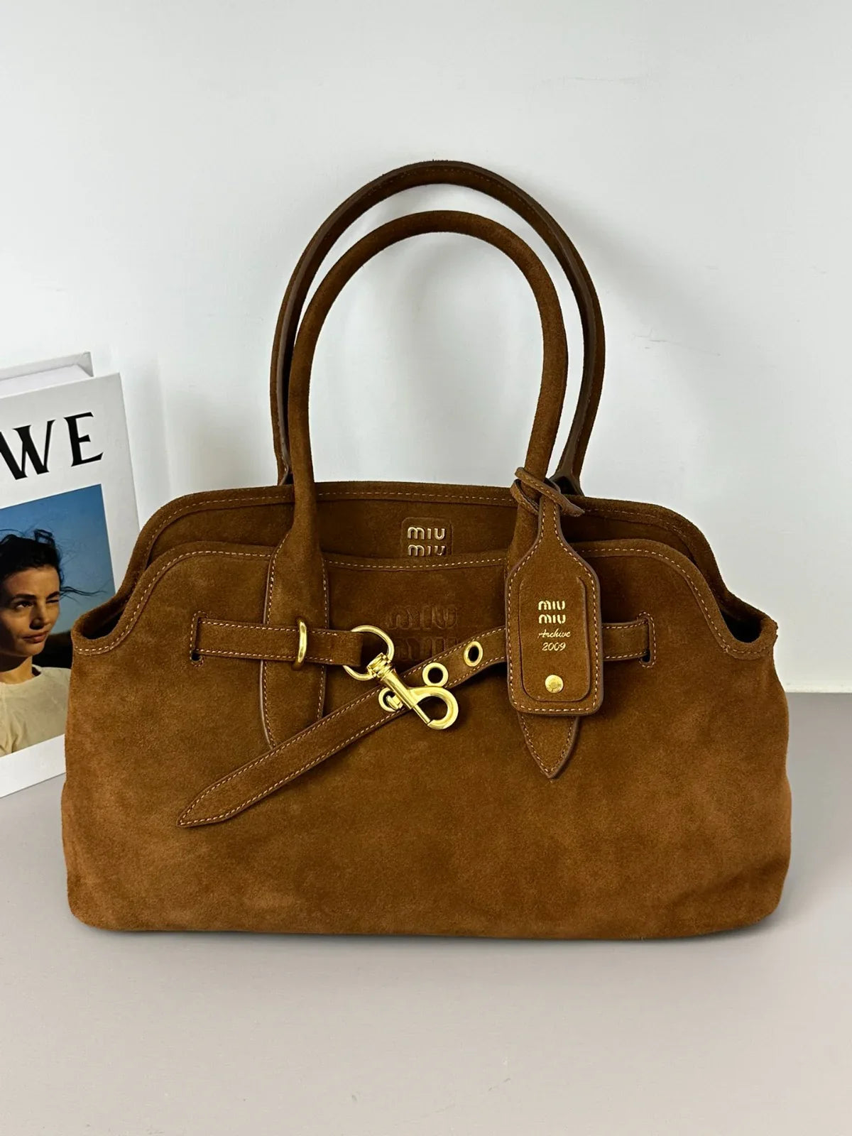 Brown handbag with gold accents on a white surface