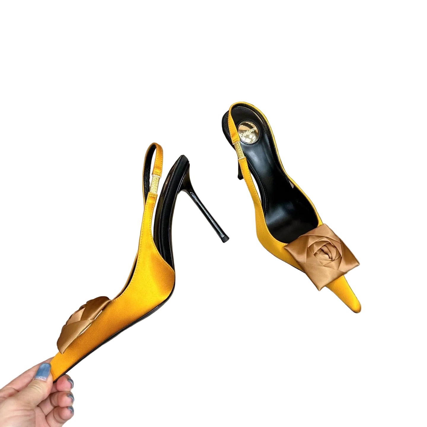 Yellow high-heeled shoes with black soles on a reflective surface.